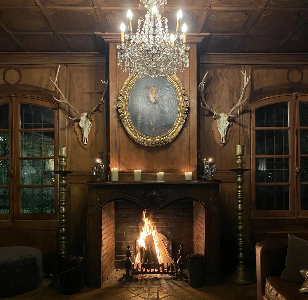 Holzvert&auml;felter Salon, brennender Kamin, Kristallleuchter und Kerzen
